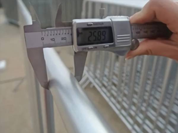 A hand is measuring the outer frame of crowd control barrier.