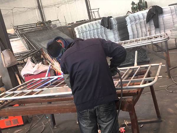 Two workers are welding crowd control barriers.