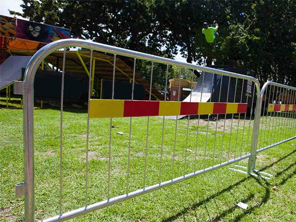 Crowd control barriers are surrounding the stage on the grassland.